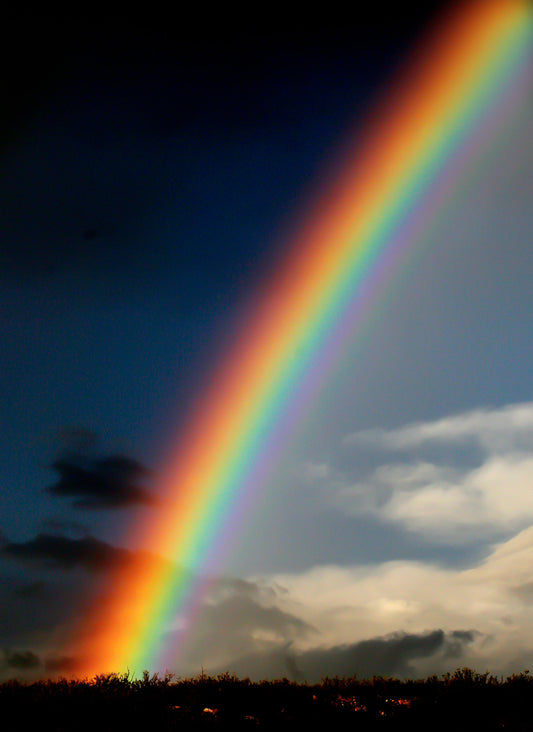 Landscape Photography print of a rainbow arching over a landscape with both dark skies and bright skies.