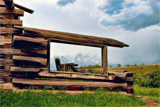 “Cabin with a View”—a fine art print of a weathered Wyoming cabin framing the Tetons under moody skies. 